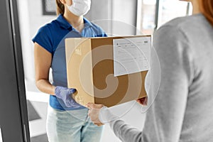 Delivery girl in face mask giving parcel to woman