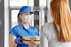 Delivery girl in mask giving pizza boxes to woman