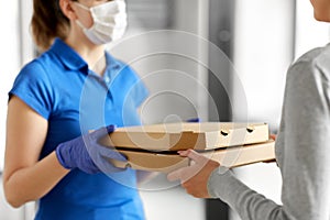 Delivery girl in mask giving pizza boxes to woman