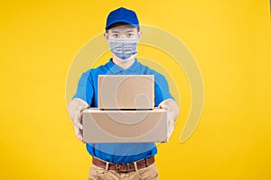 Delivery handsome man wearing and pointing mask with carton box picking up the package