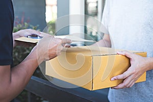 Delivery mail man giving parcel box to recipient and signature form, Young owner signing receipt of delivery package from post