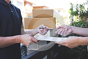 Delivery mail man giving parcel box to recipient, Young man signing receipt of delivery package from post shipment courier at home