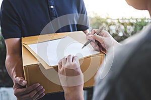 Delivery mail man giving parcel box to recipient, Young man signing receipt of delivery package from post shipment courier at home