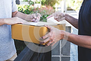 Delivery mail man giving parcel box to recipient, Young man signing receipt of delivery package from post shipment courier at home