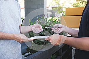 Delivery mail man giving parcel box to recipient, Young man signing receipt of delivery package from post shipment courier at home