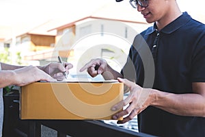 Delivery mail man giving parcel box to recipient, Young man signing receipt of delivery package from post shipment courier at home