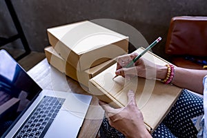 Delivery Mail Shipping smiling Woman writing an order on Delivery Box. Writing addressee on Packing