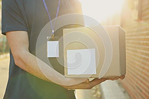 Delivery man with badge holds blank box outdoor