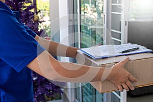 Delivery man in blue uniform handing parcel box for client  signing checklist after confirm receiving package