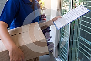 Delivery man in blue uniform handing parcel box for client  signing checklist after confirm receiving package