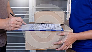 Delivery man in blue uniform handing parcel box for client  signing checklist after confirm receiving package