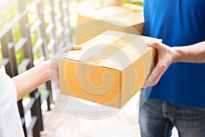 Delivery man in blue uniform handing parcel box to recipient