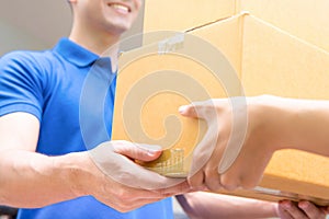 Delivery man in blue uniform handing parcel boxes to recipient