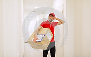 Delivery man with box and clipboard in corridor