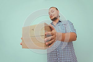 Delivery man with brown box on your home door. Light blue background. Hands hold parcel. Delivery service.