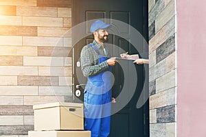 Delivery man with cardboard box giving clipboard