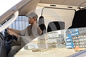 Delivery man with cardboard boxes sitting in front seat of car outside the warehouse