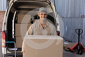 Delivery man carrying cardboard boxes outside the warehouse