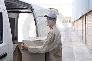 Delivery man carrying cardboard boxes outside the warehouse