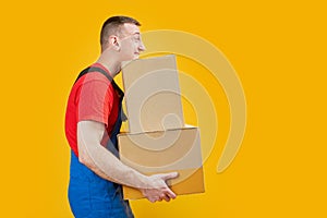 Delivery man carrying heavy boxes. Male courier with parcels isolated on yellow background. Copy space, mock up