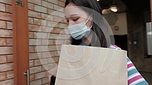 Delivery man with face mask gives parcel to an Asian woman.