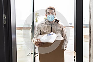 delivery man in face mask holding parcel box