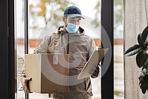 delivery man in face mask holding parcel box