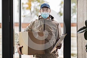 delivery man in face mask holding parcel box