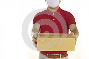 Delivery man with face mask in red cloth holding a box package.