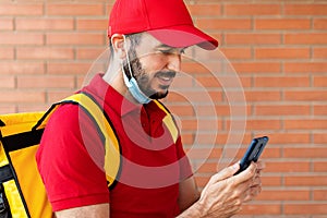 Delivery man in face mask using mobile phone while delivering packages