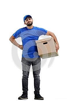 Delivery man, full-length, on a white background, with a box, hands on hips