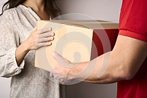 Delivery man giving cardboard box to female hand