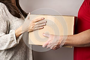 Delivery man giving cardboard box to female hand