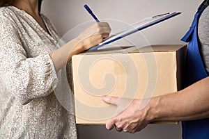 Delivery man giving cardboard box to female hand