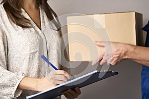 Delivery man giving cardboard box to female hand