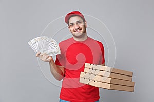 Delivery man giving hold cash money pizza boxes isolated on grey background. Professional male pizzaman employee in red