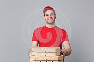 Delivery man giving hold food order pizza boxes isolated on grey background. Professional male pizzaman employee in red