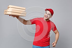 Delivery man giving hold food order pizza boxes isolated on grey background. Professional male pizzaman employee in red