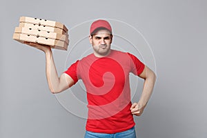 Delivery man giving hold food order pizza boxes isolated on grey background. Professional male pizzaman employee in red