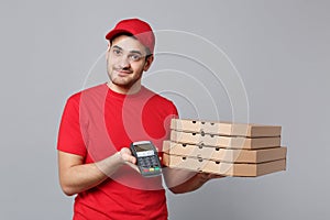 Delivery man giving hold food order pizza boxes isolated on grey background. Professional male pizzaman employee in red