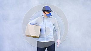 Delivery man in gloves, mask and cap holding cardboard boxes. Contactless delivery. Online shopping. Quarantine.