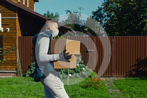 Delivery man goes to the door of the house and carries two heavy boxes