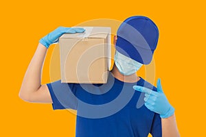 Delivery man hand in medical gloves and wearing mask holding cardboard box mockup template