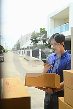 Delivery man handling a package while checking information on a smartphone