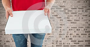 Delivery man holding box against concrete wall