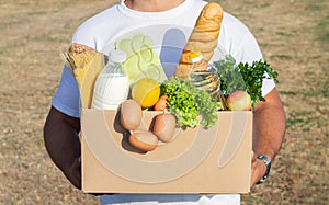 Delivery man holding box with fresh food groceries outdoors