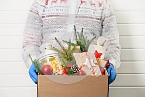 Delivery man holding cardboard box with gifts on white background. Christmas safe delivery. Donation concept