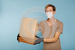 Delivery man holding cardboard boxes in black medical rubber gloves and mask. Fast and free Delivery transport . Online shopping