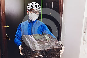 Delivery man holding cardboard boxes in medical rubber gloves and mask. copy space. Fast and free Delivery transport