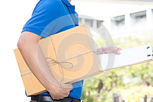 Delivery man holding a parcel box and white paper on clipboard